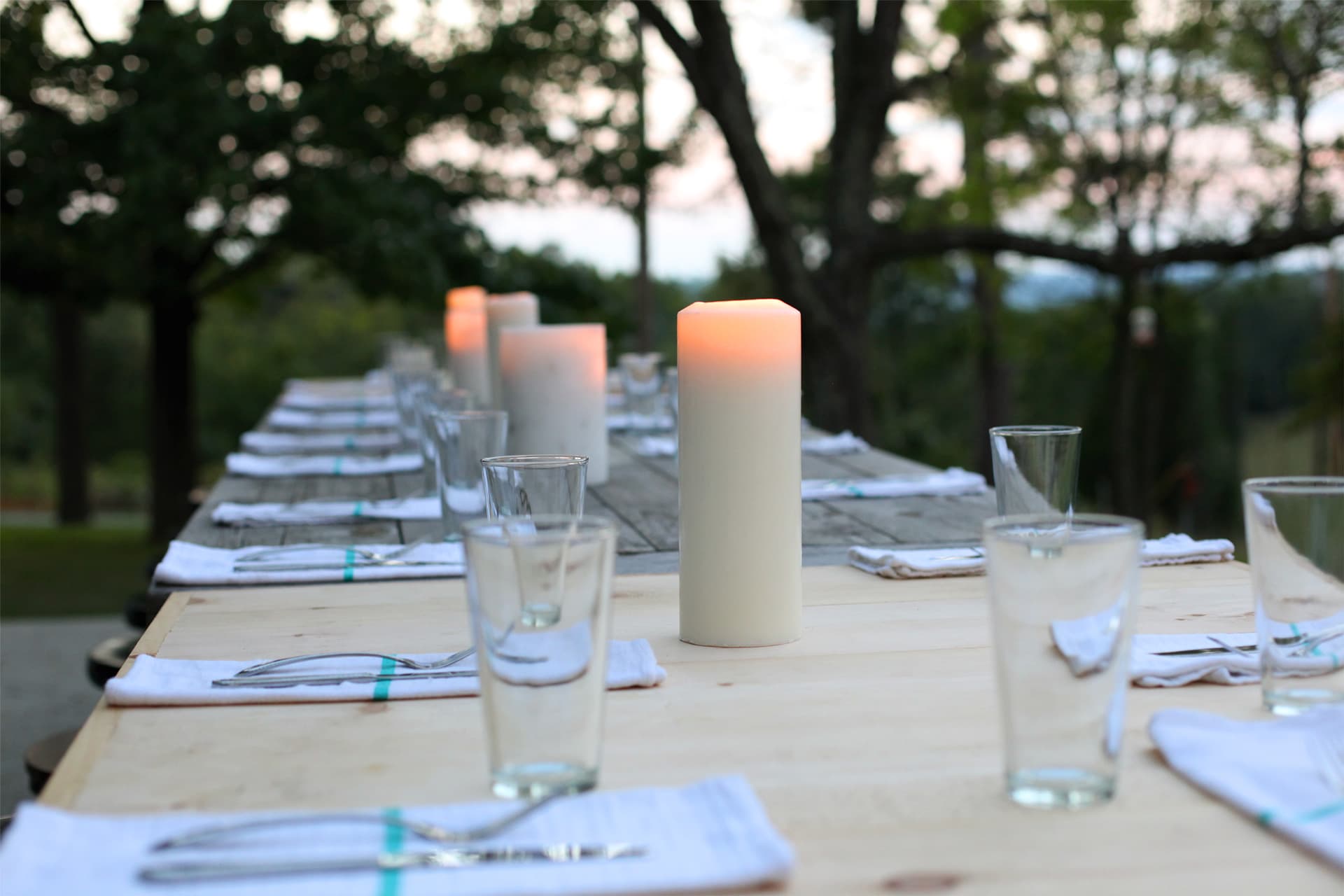 Long outdoor dining table set with candles at dusk