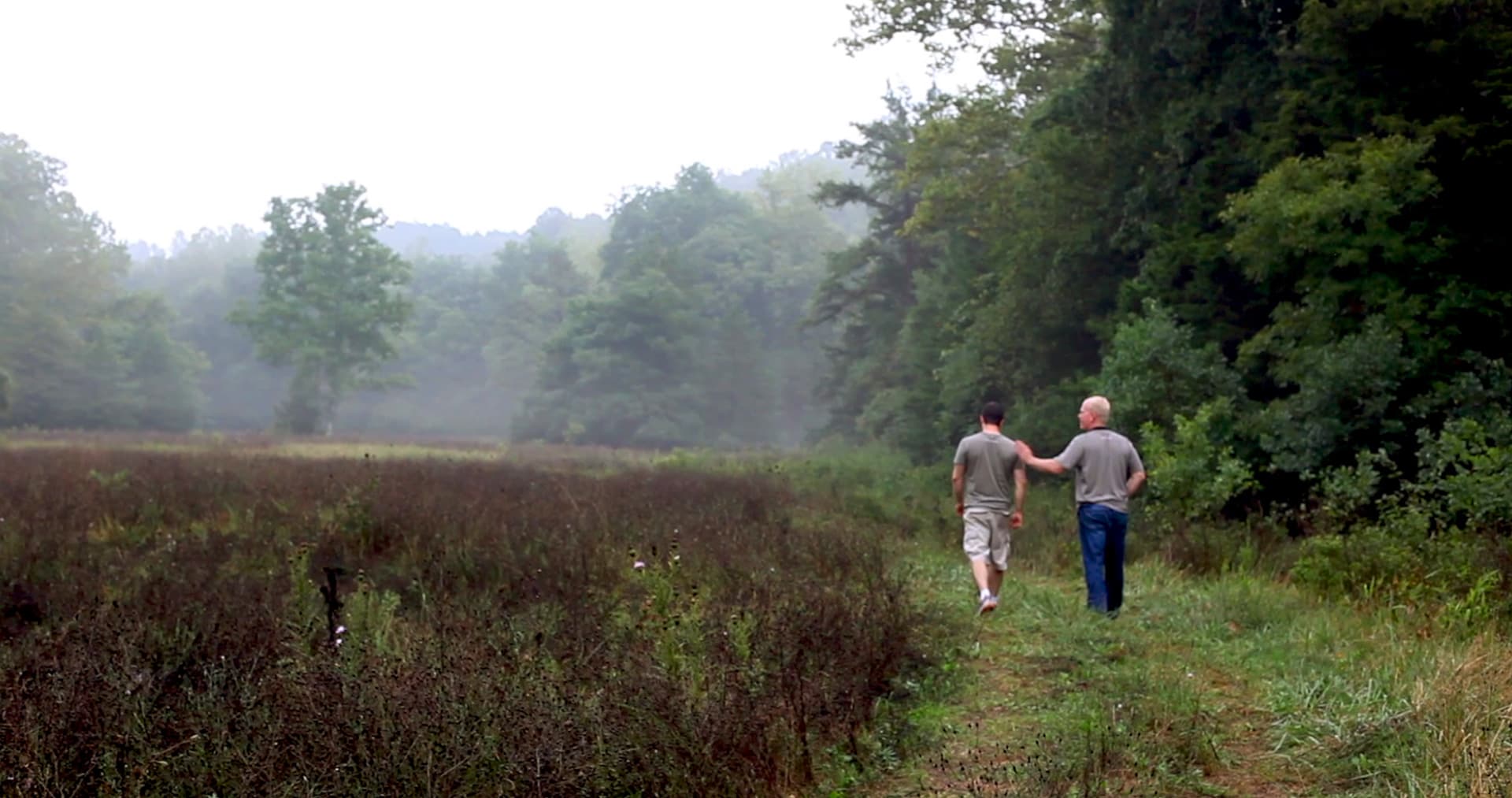 Two people walking along a misty trail